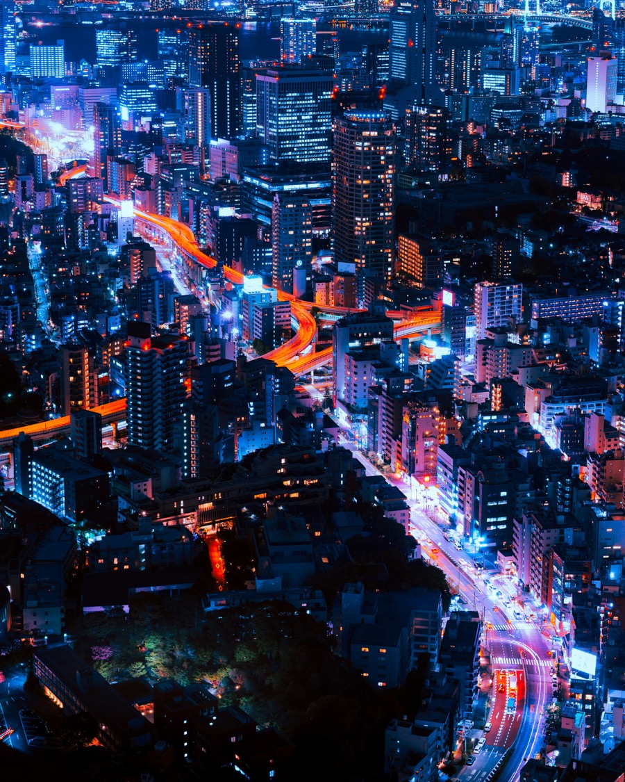 Aerial night view of a city's illuminated highways and skyscrapers